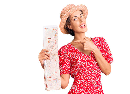 Young beautiful woman wearing summer hat holding map smiling happy pointing with hand and finger