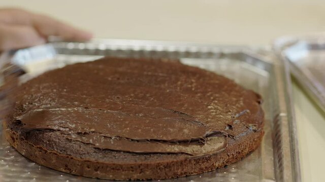 Young Girl Putting Icing On A Chocolate Cake Top