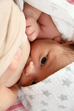 mother breastfeeding baby wrapped up in blanket and just been cared for after having a good sleep in bed stock photo