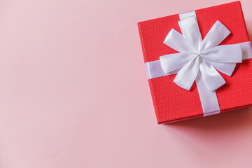 Christmas New Year birthday valentine celebration present romantic concept. Simply minimal design red gift box isolated on pastel pink colorful background. Flat lay top view, copy space
