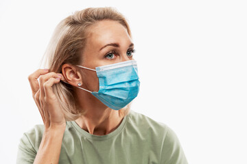 Young woman puts on a medical mask. Coronavirus pandemic. Close-up. White background.