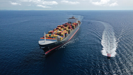 Aerial drone photo of huge container tanker ship carrying truck size colourful containers in deep...