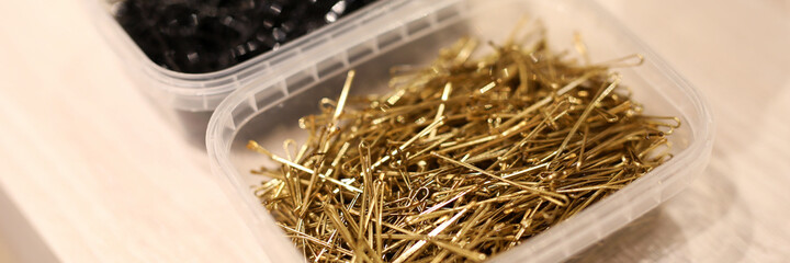 Black and gold metal hairpins in plastic container