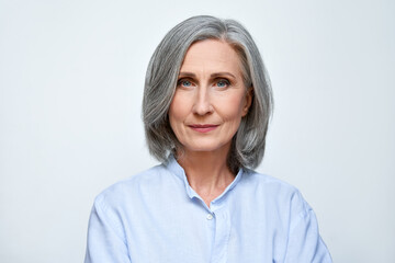 Confident beautiful mature business woman standing isolated on white background. Older senior businesswoman, 60s grey haired lady professional looking at camera, close up face headshot portrait. - obrazy, fototapety, plakaty