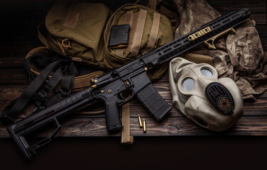 Modern carbine, backpack and gas mask on a wooden back. A set of fighter ready for any battle conditions.
