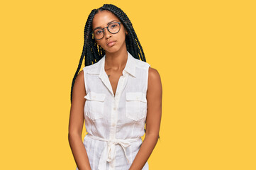 Beautiful hispanic woman wearing casual clothes and glasses relaxed with serious expression on...