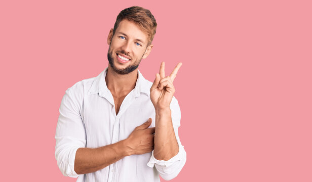 Young caucasian man wearing casual clothes smiling with happy face winking at the camera doing victory sign. number two.