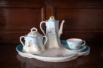 antique porcelain service - a teapot, two cups and saucers in blue and white with flowers - stands on the chest of drawers.