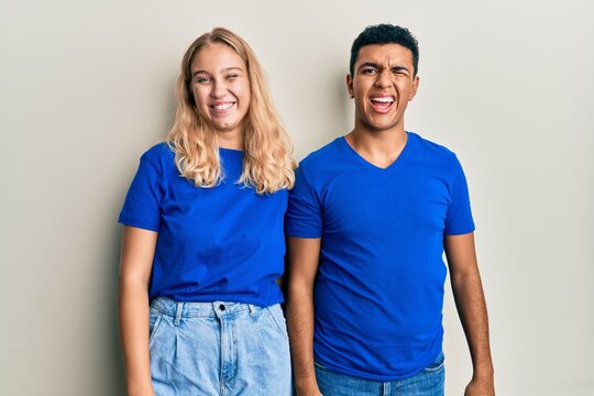 Young interracial couple wearing casual clothes winking looking at the camera with sexy expression, cheerful and happy face.