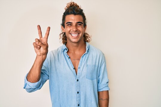 Young hispanic man wearing summer style smiling with happy face winking at the camera doing victory sign. number two.