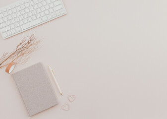 feminine desk workspace with notebook on dusty pink background.
