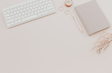 feminine desk workspace with notebook on dusty pink background.