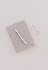 feminine desk workspace with notebook on dusty pink background.