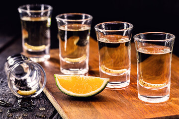 several glasses of Mezcal (or mescal) is an exotic alcoholic drink from Mexico, distilled, variation of tequila, consumed with orange, and with a larva inside