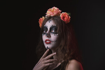 Girl with skeleton makeup and flowers in her hair on a dark background