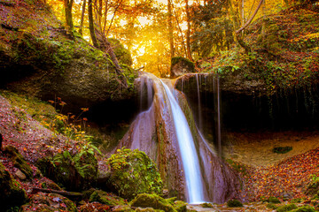 Waterfall in autumn with orange and yellow colors. Running clear, cold water in a forrest during autumn.