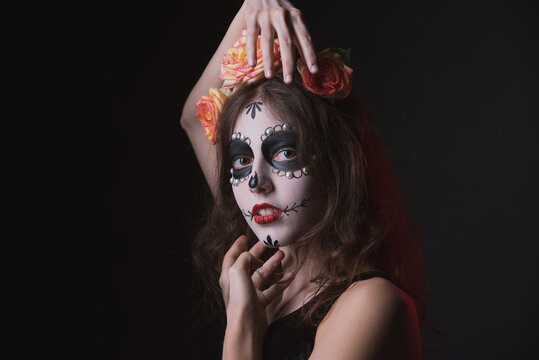 Girl with skeleton makeup and flowers in her hair on a dark background