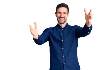 Young handsome man wearing casual shirt looking at the camera smiling with open arms for hug. cheerful expression embracing happiness.