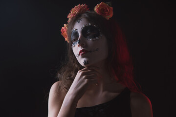 Girl with skeleton makeup and flowers in her hair on a dark background