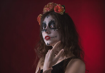 Girl with skeleton makeup and flowers in her hair on a dark background