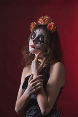 Girl with skeleton makeup and flowers in her hair on a dark background