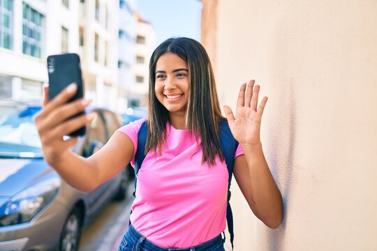 Young latin student girl doing video call using smartphone at university campus.