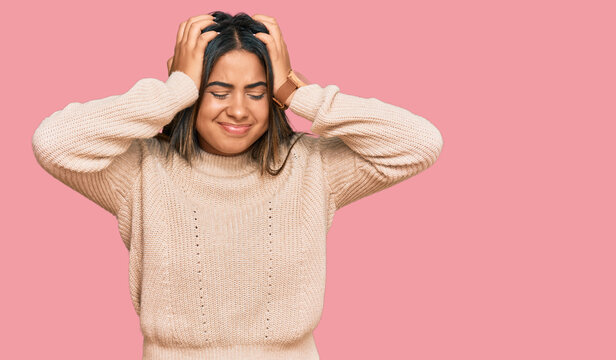 Young latin girl wearing wool winter sweater suffering from headache desperate and stressed because pain and migraine. hands on head.