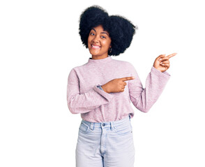 Young african american girl wearing casual clothes smiling and looking at the camera pointing with two hands and fingers to the side.