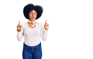 Young african american girl wearing casual clothes and glasses amazed and surprised looking up and pointing with fingers and raised arms.