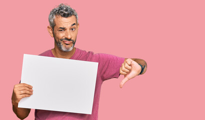 Middle age grey-haired man holding blank empty banner with angry face, negative sign showing...