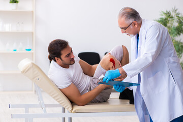 Obraz premium Leg injured man visiting old doctor in first aid concept