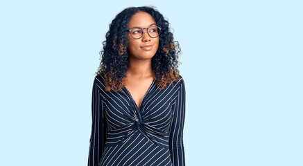 Young african american woman wearing casual clothes and glasses smiling looking to the side and staring away thinking.