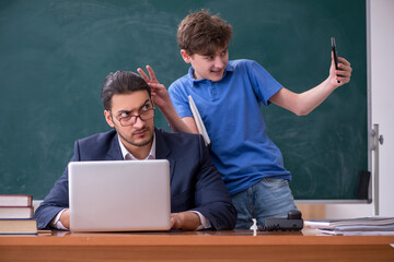 Young male teacher and schoolboy in the classroom