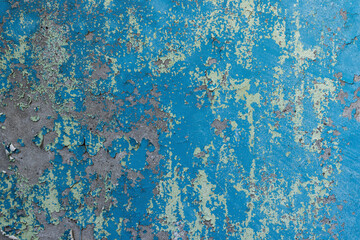 Peeling paint on the wall. Old concrete wall with cracked flaking paint. Weathered rough painted surface with patterns of cracks and peeling. Grunge texture for background and design. High resolution.