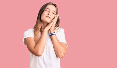 Beautiful caucasian woman wearing casual white tshirt sleeping tired dreaming and posing with hands together while smiling with closed eyes.