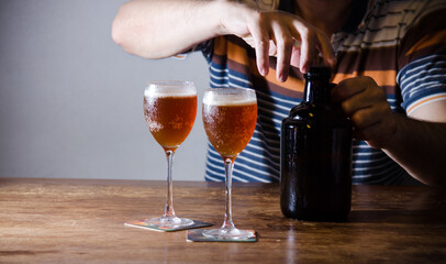 Unrecognizable man serving homebrew in glasses with growler.