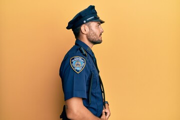 Handsome hispanic man wearing police uniform looking to side, relax profile pose with natural face...