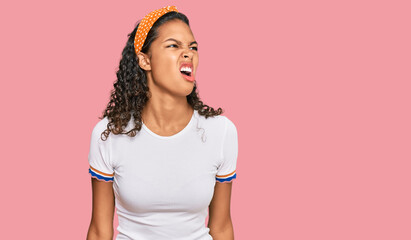 Young african american girl wearing casual clothes angry and mad screaming frustrated and furious,...