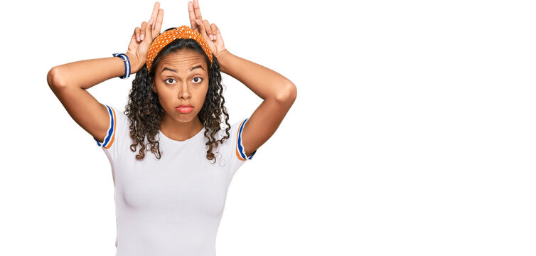 Young african american girl wearing casual clothes doing bunny ears gesture with hands palms looking cynical and skeptical. easter rabbit concept.