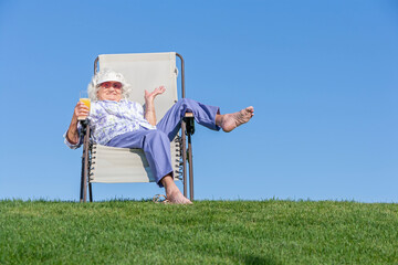 A senior elderly woman relaxing outside on a lounge chair.