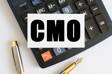 On the table there is a pen, a calculator and a business card on which the text is written CMO. CHIEF MARKETING OFFICER