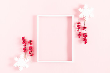 Christmas, winter composition. Xmas decorations, photo frame, red berries, snowflakes on pastel pink background. Christmas, New Year, winter concept. Flat lay, top view, copy space