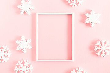 Christmas, winter composition. Xmas decorations, photo frame, snowflakes on pastel pink background. Christmas, New Year, winter concept. Flat lay, top view, copy space