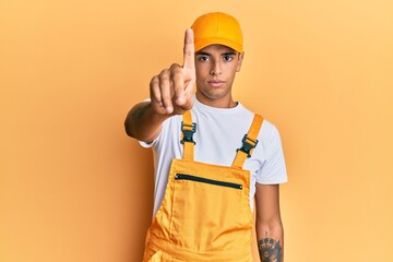 Young handsome african american man wearing handyman uniform over yellow background pointing with finger up and angry expression, showing no gesture