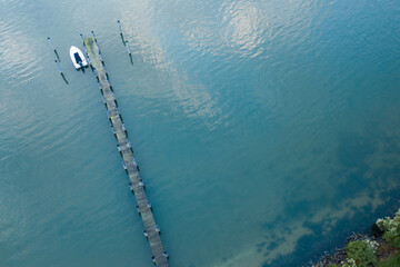 Aerial of a long dock with a white boat in aqua waters.
