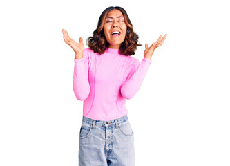 Young beautiful mixed race woman wearing pink shirt celebrating mad and crazy for success with arms raised and closed eyes screaming excited. winner concept