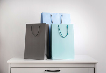 Paper shopping bags on white chest of drawers against light background