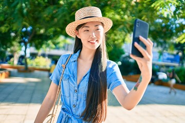 Fototapeta premium Young chinese tourist woman making selfie by the smartphone at street of city.
