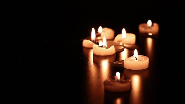 Group of candles burning in a dark environment.