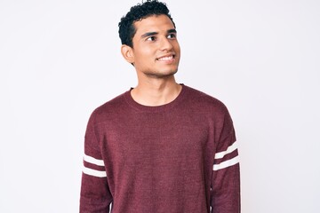 Young handsome hispanic man over white background looking to side, relax profile pose with natural face and confident smile.